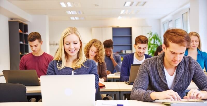 Many students in school working with computers and tablet PCs